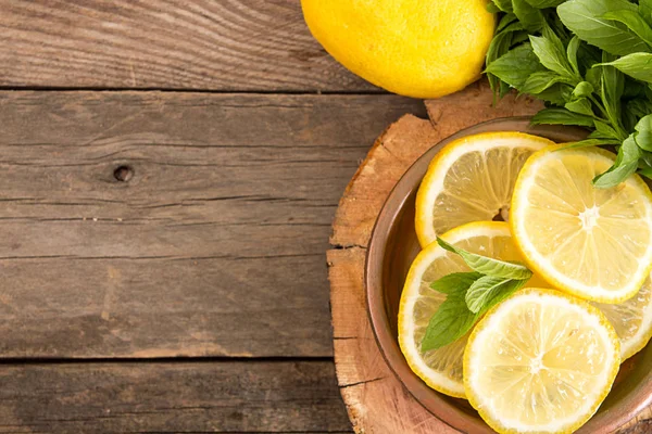 Bundle of mint and slices of lemon on old wooden background. Cop — Stock Photo, Image