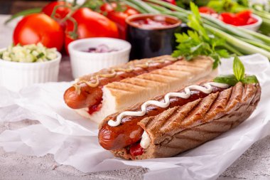 Sosisli sandviçler, beyaz arka planda domatesler. Fast food, Amerikan geleneği.