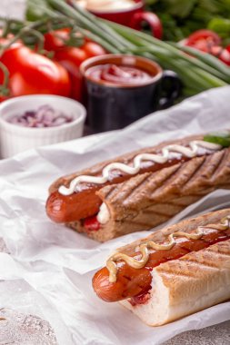 Sosisli sandviçler, beyaz arka planda domatesler. Fast food, Amerikan geleneği.