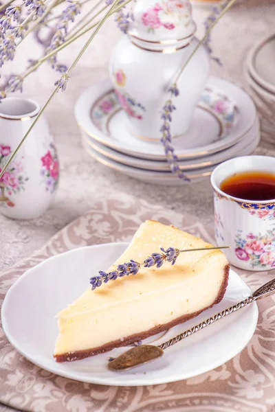 Piece of cheesecake on white plate, cup of tea, vintage tablewar — Stock Photo, Image