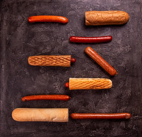 Інгредієнти для хот-догів булочки різні ковбаски на чорному бетоні — стокове фото