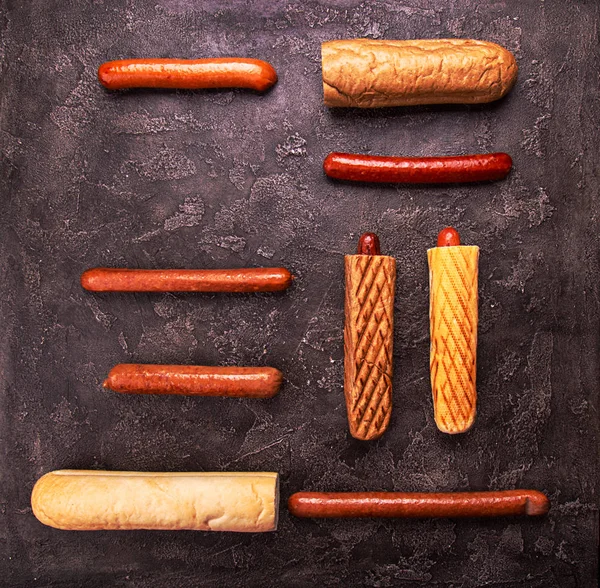 Інгредієнти для хот-догів булочки різні ковбаски на чорному бетоні — стокове фото