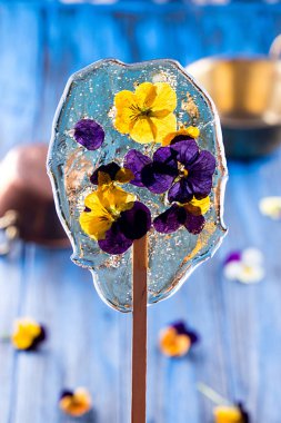 Yenebilir menekşe çiçekli güzel lolipop karamel koyu mavi arka planda.. 