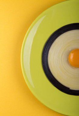 Sarı arka planda yumurta sarısı ile siyah beyaz linguini makarna ile zeytin rengi tabağın yarısı. Üst görünüm