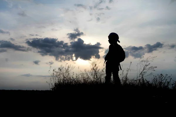 En liten pojke står på toppen och tittar in i fjärran. — Stockfoto