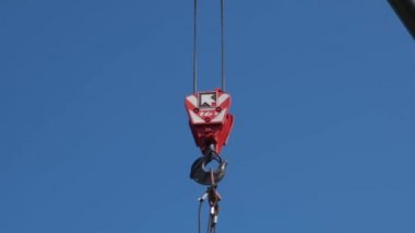 Gökyüzündeki patlamadan sarkan bir inşaat vincinin kırmızı kancası.