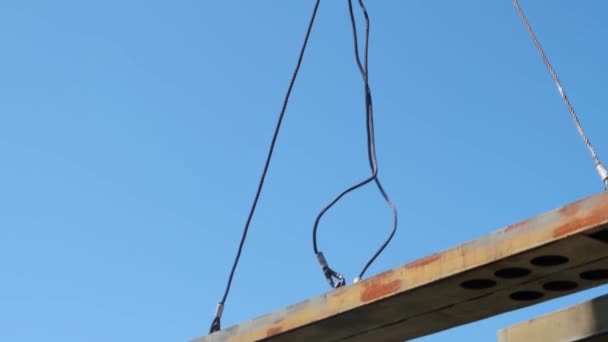 On a summer day, the green part of the bridge rises carefully and slowly moves red hook of a construction crane through the construction site — Stock Video