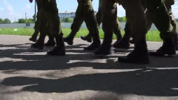 Cadets, soldiers marching in a group along the wet road in black boots and camouflage uniforms. The military carry out a combat mission