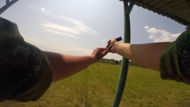 Bir asker siyah bir Pov savaş tabancasıyla hedefleri vuruyor. Cephaneyi sol elle yerleştirir