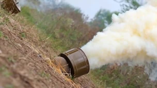 Bomba de humo militar en el bosque, mucho humo amarillo seco en el césped. Imagen colorida hierba verde. Entrenamiento de combate. Contaminación ambiental — Vídeo de stock