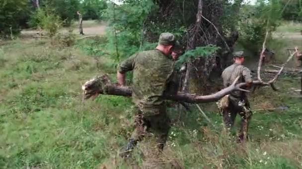 ロシア Maykop 2019年8月2日 制服を着た兵士2人が森の中で丸太を担いでいる 敵士官候補生との戦いに備えて — ストック動画