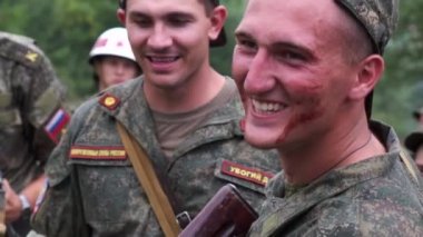 Rusya, Maykop - 2 Ağustos 2019. Askeri üniformalı kanlı bir asker Ak-74 askeri silahından ateş ettikten sonra gülümsüyor.