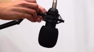 Müzik ve ses kaydetmek için profesyonel bir mikrofonun ortaya çıkması. Ön geçirmez standı ve beyaz arka planda kablosu olan pratik mikrofon kurulumu.