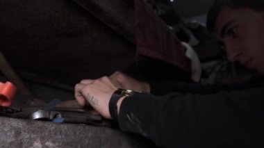 MOSKOW - 9 Mart. Adam eski bir fabrika rafından çeşitli aletler seçiyor, garaj masası - endüstriyel tema. Çeşitli donanım bağlayıcılarının, somunların, cıvataların, anahtarların ve diğer parçaların ve araçların kapatılması