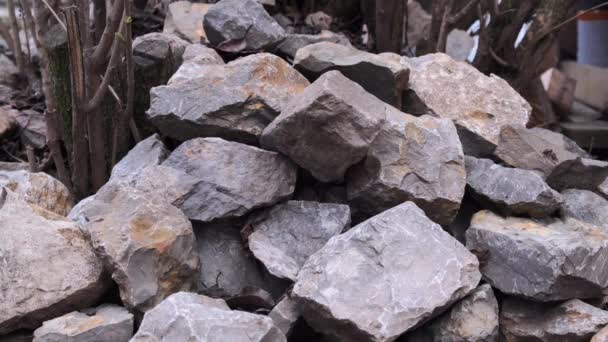 Closeup de pedras cinzentas e brancas desfocadas de várias formas. De cima 3 pedras caem em uma pilha comum. Mova o ângulo da câmera da esquerda para a direita . — Vídeo de Stock