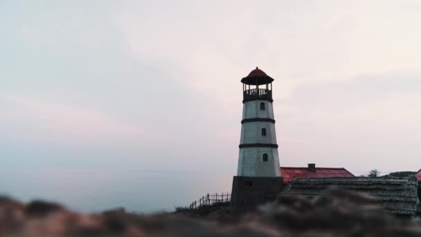 村の海岸沿いに家がある赤い上と近くのボートと小さな白い灯台 夕方の夕日 ピンクブルーの空とふわふわの白い雲 — ストック動画