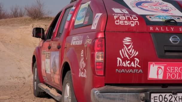 Moesow, Rusland - APRIL 20. In een Nissan Navara SUV. Een rode pick-up truck met 4x4 stickers staat op een zandveld bij de heuvel. Een zwerfhond rent voor een pick-up auto. — Stockvideo