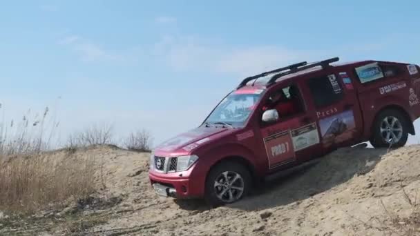MOSCOW, RUSSIA - April 20.开越野车尼桑 · 纳瓦拉红色四轮驱动皮卡在战场上漂流。车轮下飞扬着灰尘.小货车在沙滩上行驶。汽车从陡峭的山下下来 — 图库视频影像