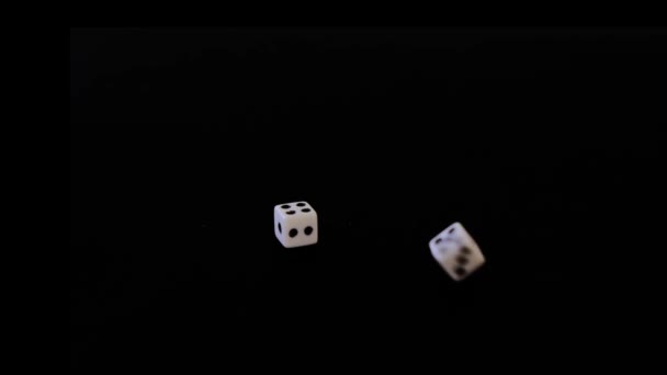 Sept dés tombent à leur tour, des cubes blancs volent sur un fond noir. Les cubes tombent, tournent sur une surface noire. Arrête en vue. Concept d'affaires et de casino ou de jeu. Gros plan . — Video