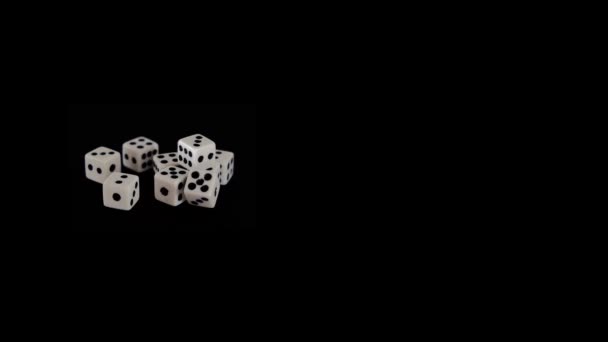 Acht witte dobbelstenen op een zwarte achtergrond voor het spel. Kubussen liggen op een zwart oppervlak. Soepele beweging in zicht. Begrip bedrijf en casino of gokken. Close-up. — Stockvideo