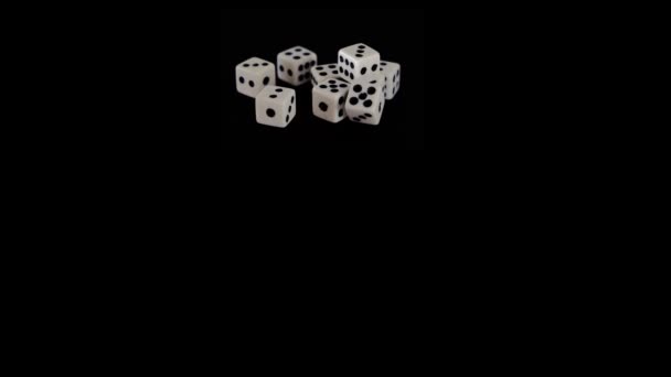 Acht witte dobbelstenen op een zwarte achtergrond voor het spel. Kubussen liggen op een zwart oppervlak. Soepele beweging in zicht. Begrip bedrijf en casino of gokken. Close-up. — Stockvideo