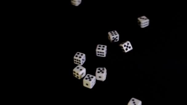 2つの側面から白いキューブは黒の背景に飛んでいます。ダイスは黒い表面で回転し、跳ねる。ビジネスやカジノやギャンブルの概念。接近中だ。スローモスローモスローモーション — ストック動画