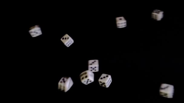 De deux côtés, des cubes blancs volent sur un fond noir. Les dés tournent et rebondissent sur une surface noire. Concept d'affaires et de casino ou de jeu. Gros plan. Ralenti, ralenti, ralenti — Video