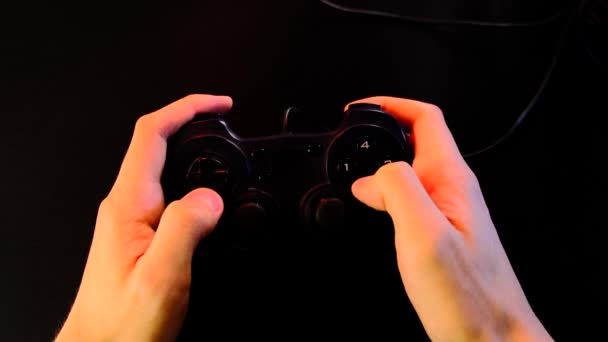 手を閉じる 男はゲーム機でビデオゲームをプレイするために黒のコントローラーを使用しています 大画面 プロジェクターやテレビの前でゲームパッド 光の変化 ライフスタイルの概念Covid 19の分離の人々 — ストック動画