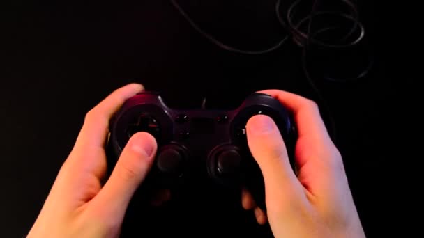 手を閉じる 男はゲーム機でビデオゲームをプレイするために黒のコントローラーを使用しています 大画面 プロジェクターやテレビの前でゲームパッド 光の変化 ライフスタイルの概念Covid 19の分離の人々 — ストック動画