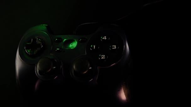 ゲーム機でビデオゲームをプレイするブラックコントローラー ゲームパッド パノラマカメラシーンをクローズアップ表示します ライトランプは青 緑に変わります — ストック動画