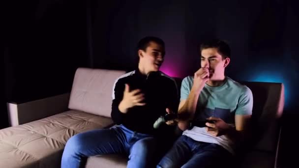 Dos Jóvenes Ríen Niños Sentados Sofá Frente Televisor Jugando Una — Vídeos de Stock