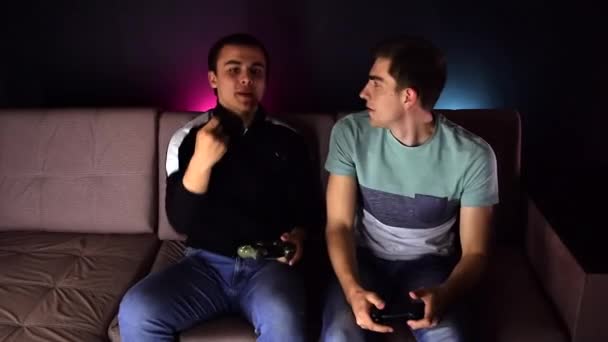 Zwei Junge Männer Sitzen Auf Der Couch Vor Dem Fernseher — Stockvideo