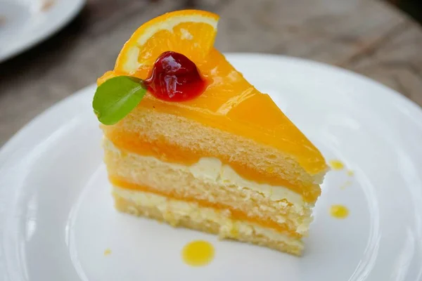 orange cake with orange and cherry topping on the wood table