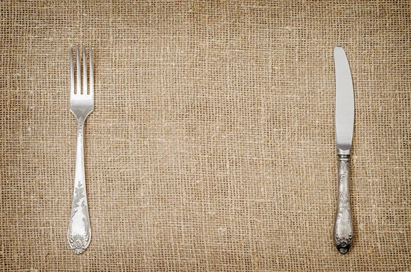 Llinen achtergrond met oude zilveren vork en mes — Stockfoto
