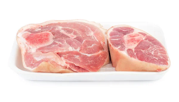 Plakje rauwe varkensvlees knokkel in een plastic container geïsoleerd — Stockfoto