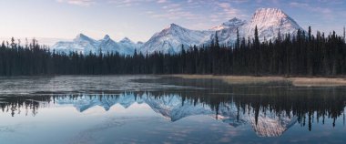 İlk kar, Bow River 'daki Üç Kız Kardeş Tepesi' nin neredeyse mükemmel bir yansıması. Banff Ulusal Parkı 'ndaki Canmore, Alberta Canada' da kış atmosferinde karla kaplı bir kış dağını kapladı. Güzel gün