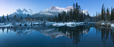 İlk kar, Bow River 'daki Üç Kız Kardeş Tepesi' nin neredeyse mükemmel bir yansıması. Banff Ulusal Parkı 'ndaki Canmore, Alberta Canada' da kış atmosferinde karla kaplı bir kış dağını kapladı. Güzel gün