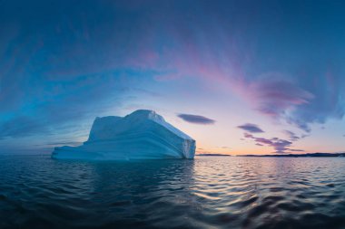 Early morning summer alpenglow lighting up icebergs during midnight season. Ilulissat, Greenland. Summer Midnight Sun and icebergs. Blue ice in icefjord. Affected by climate change and global warming.  clipart