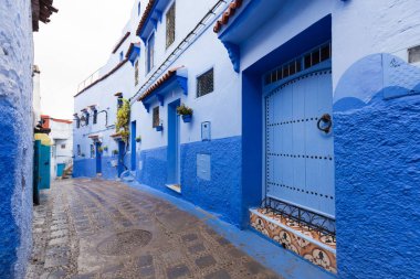 Chefchaouen, Fas, Afrika 'daki geleneksel ve tipik mimari detaylar ve mavi duvarlı ve çeşitli nesnelerle süslenmiş mavi Medine' nin güzel caddesi..