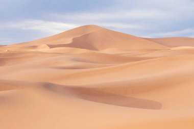 Gün batımında Merzouga, Fas, Afrika yakınlarında çöl manzaralı kum tepeleri. Keşif ve macera yolculuğu konsepti. Çöl kumullarının üzerinde güneş ışığı.