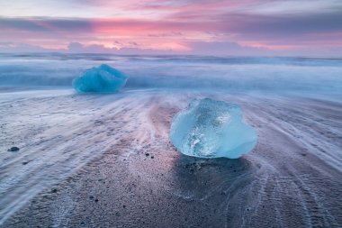 İzlanda 'nın ünlü Diamond plajında güzel bir gün batımı. Bu kum lav plajı, İzlanda 'nın güneydoğusundaki siyah kum plajlı buzul gölü Jokulsarlon Buz Kayası' nın yakınına yerleştirilmiş birçok dev buz mücevheriyle doludur.