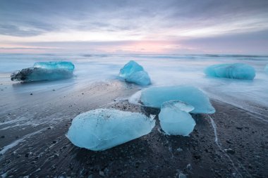İzlanda 'nın ünlü Diamond plajında güzel bir gün batımı. Bu kum lav plajı, İzlanda 'nın güneydoğusundaki siyah kum plajlı buzul gölü Jokulsarlon Buz Kayası' nın yakınına yerleştirilmiş birçok dev buz mücevheriyle doludur.