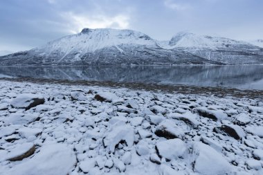 Karlı fiyortların ve dağ sırasının panoraması, Senja, Norveç İnanılmaz Norveç deniz manzarası popüler turistik cazibe merkezi. En ünlü seyahat yerleri. Muhteşem kış manzarası içinde güzel bir gün batımı