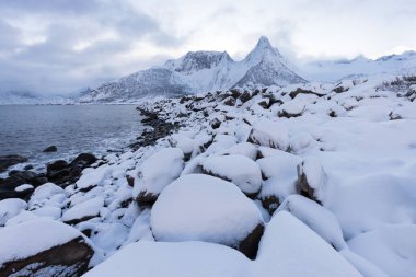 Karlı fiyortların ve dağ sırasının panoraması, Senja, Norveç İnanılmaz Norveç deniz manzarası popüler turistik cazibe merkezi. En ünlü seyahat yerleri. Muhteşem kış manzarası içinde güzel bir gün batımı