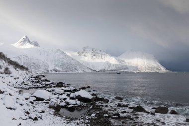 Karlı fiyortların ve dağ sırasının panoraması, Senja, Norveç İnanılmaz Norveç deniz manzarası popüler turistik cazibe merkezi. En ünlü seyahat yerleri. Muhteşem kış manzarası içinde güzel bir gün batımı
