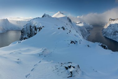 Karlı fiyortların ve dağ sırasının panoraması, Senja, Norveç İnanılmaz Norveç deniz manzarası popüler turistik cazibe merkezi. En ünlü seyahat yerleri. Muhteşem kış manzarası içinde güzel bir gün batımı