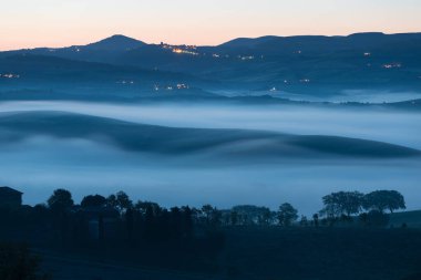 Tuscany 'nin yeşil bahar manzarasının güzel renkleri. İtalya 'nın en popüler yeri. Yeşil tarlalar, mavi gökyüzü ve Siena yakınlarındaki Cypress ağaçları manzaralı yol. Güneşli, sisli bir sabah