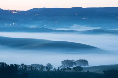 Tuscany 'nin yeşil bahar manzarasının güzel renkleri. İtalya 'nın en popüler yeri. Yeşil tarlalar, mavi gökyüzü ve Siena yakınlarındaki Cypress ağaçları manzaralı yol. Güneşli, sisli bir sabah