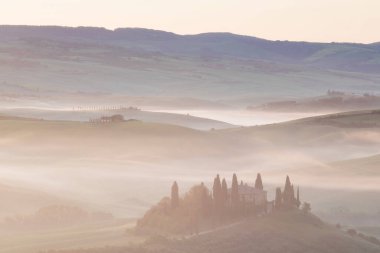 Tuscany 'nin yeşil bahar manzarasının güzel renkleri. İtalya 'nın en popüler yeri. Yeşil tarlalar, mavi gökyüzü ve Siena yakınlarındaki Cypress ağaçları manzaralı yol. Güneşli, sisli bir sabah