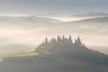 Tuscany 'nin yeşil bahar manzarasının güzel renkleri. İtalya 'nın en popüler yeri. Yeşil tarlalar, mavi gökyüzü ve Siena yakınlarındaki Cypress ağaçları manzaralı yol. Güneşli, sisli bir sabah